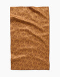 Aubrey Fairchilds Pumpkin Patchwork tea towel features a brown background with an all-over pattern of darker brown, outlined pumpkins, shown flat with subtle wrinkles.