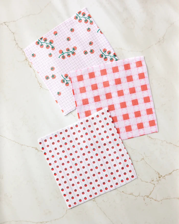 Three "Quilt Tomato Harvest" dishcloths by Brittany Jepsen, crafted from recycled materials, are displayed on marble. Featuring floral, gingham check, and polka dot patterns, this eco-friendly set adds charm to any kitchen.