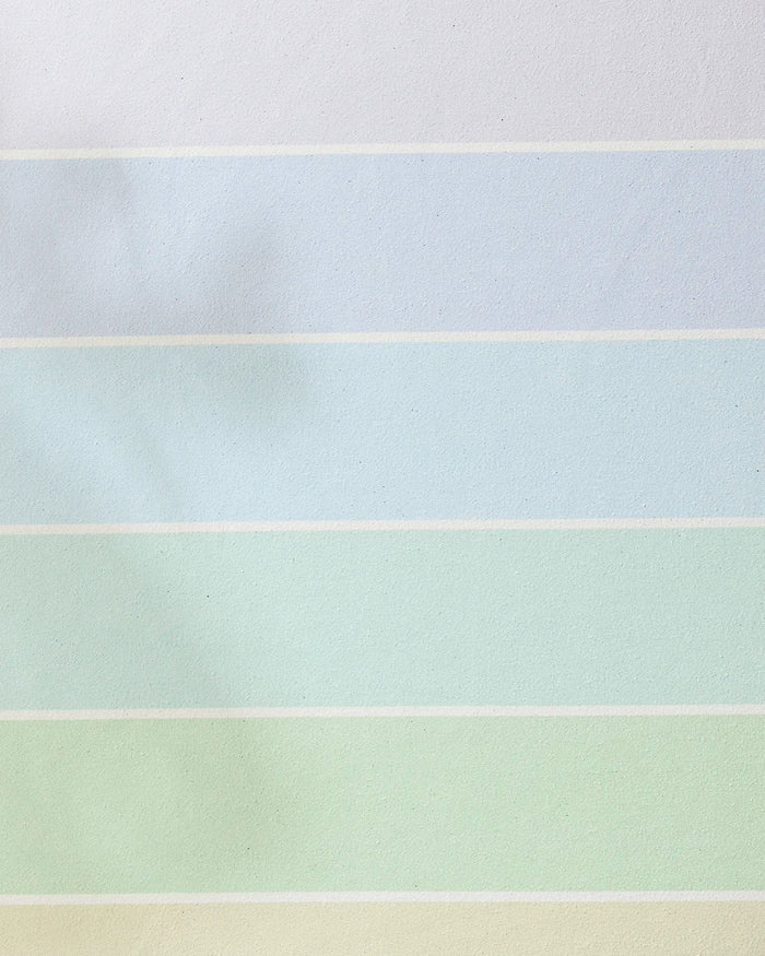 The GEOMETRY Rainbow Pastel recycled yoga towel features wide horizontal stripes in white, blue, green, and yellow for a calming, stylish look—perfect for an eco-friendly, non-slip yoga practice.