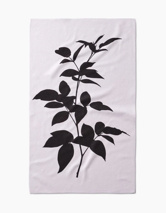 A white rectangular PrintedPlant Raspberry Tea Towel features a bold black silhouette of a leafy plant with branches, leaves, and buds, centered on light Geoweave™ fabric made from post-consumer recycled materials.