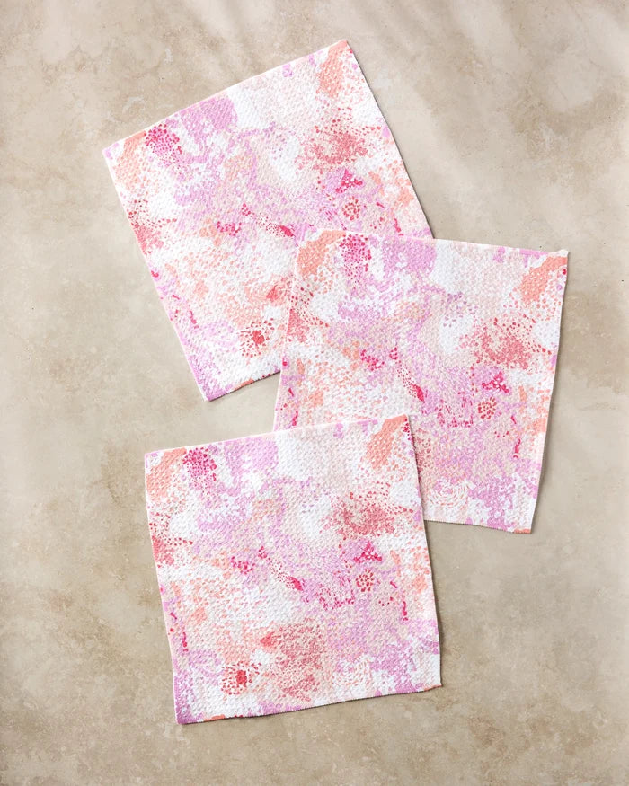 Three Elisabeth Wing Rawhide dishcloths are arranged on a beige marble surface, overlapping slightly in a casual, diagonal layout.