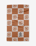 The Realm Refillery Checker by Realm Refillery is a checkered tea towel with rusty brown and white squares, sunflower accents, and NO SPACE FOR WASTE on one white square, all crafted from recycled materials.