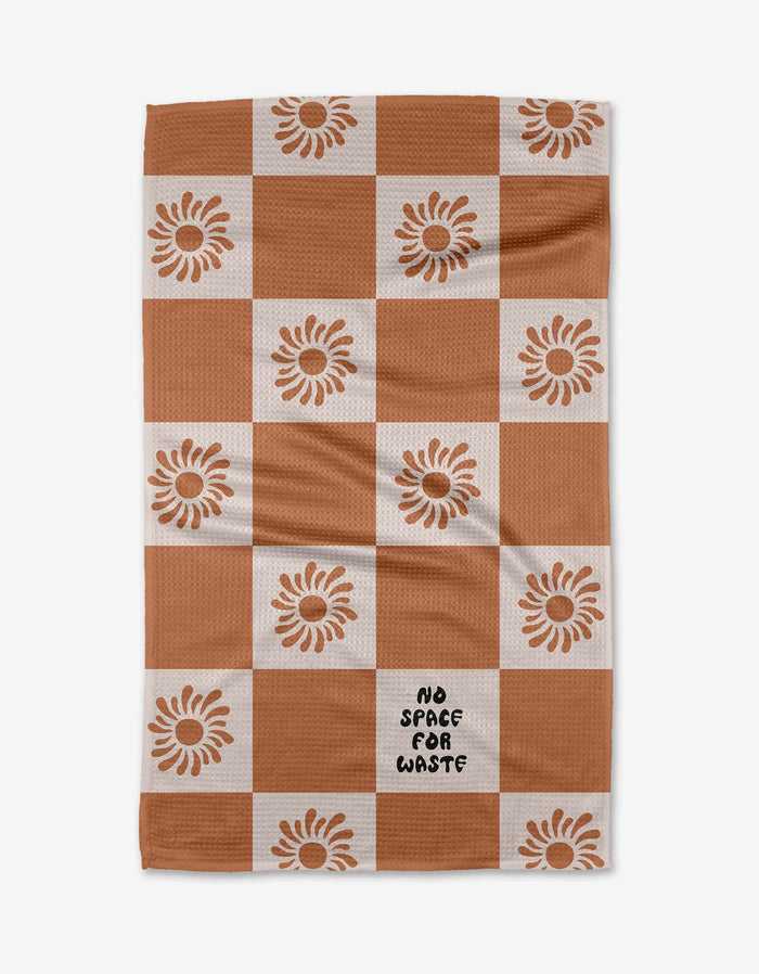 The Realm Refillery Checker by Realm Refillery is a checkered tea towel with rusty brown and white squares, sunflower accents, and NO SPACE FOR WASTE on one white square, all crafted from recycled materials.