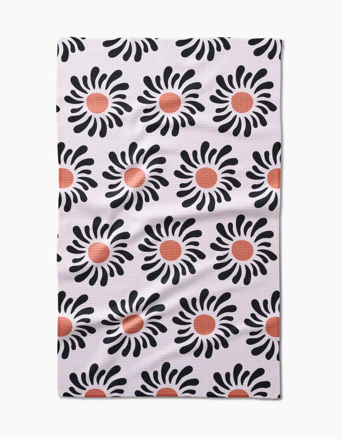 The Realm Refillery tea towel features a white background with rows of black flowers accented by red-orange centers. Made from eco-friendly Geoweave fabric, this stylish and sustainable design comes from Realm Refillery.