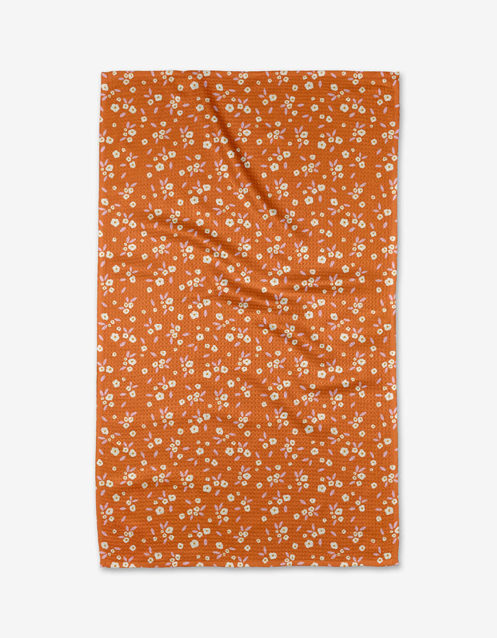 A Red Field of Flowers tea towel by Megan Roy, featuring a white floral pattern on soft Geoweave fabric, is shown laid flat on a white background.