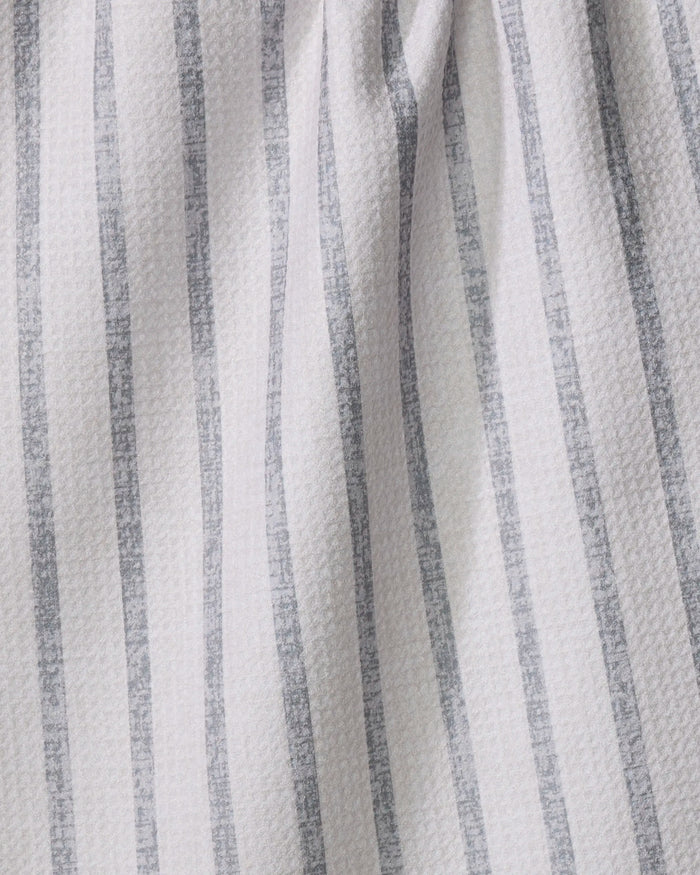 Close-up of the Becki Owens Ren Grey tea towel, featuring vertical gray stripes on a light background with a textured woven surface. Faint folds and shadows enhance the ultra-absorbent towel’s gently draped look.