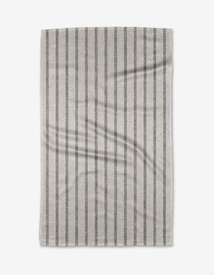 A rectangular beige Becki Owens Ren Grey tea towel made from Geoweave fabric, with evenly spaced vertical dark gray stripes and slight visible creases, is shown flat on a white background.