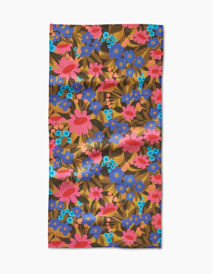 The Retro Garden bar towel by Lisa Nelson features a vibrant floral pattern on a brown background and is crafted from soft Geoweave fabric for enhanced absorbency.