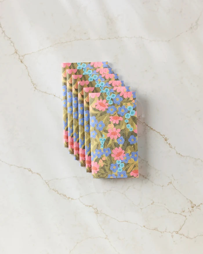 Six Retro Garden chocolate bars by Lisa Nelson, each wrapped in pastel floral-patterned, eco-friendly kitchen towels, are fanned out on a marble surface.