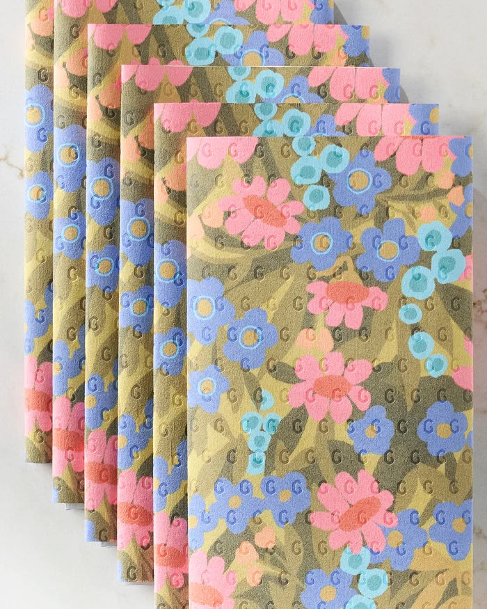 Six envelopes from Lisa Nelson’s Retro Garden set are arranged in a fan shape, featuring gold backgrounds with a repeating G print and pink, blue, and purple floral designs—perfect for gifting with eco-friendly kitchen towels.