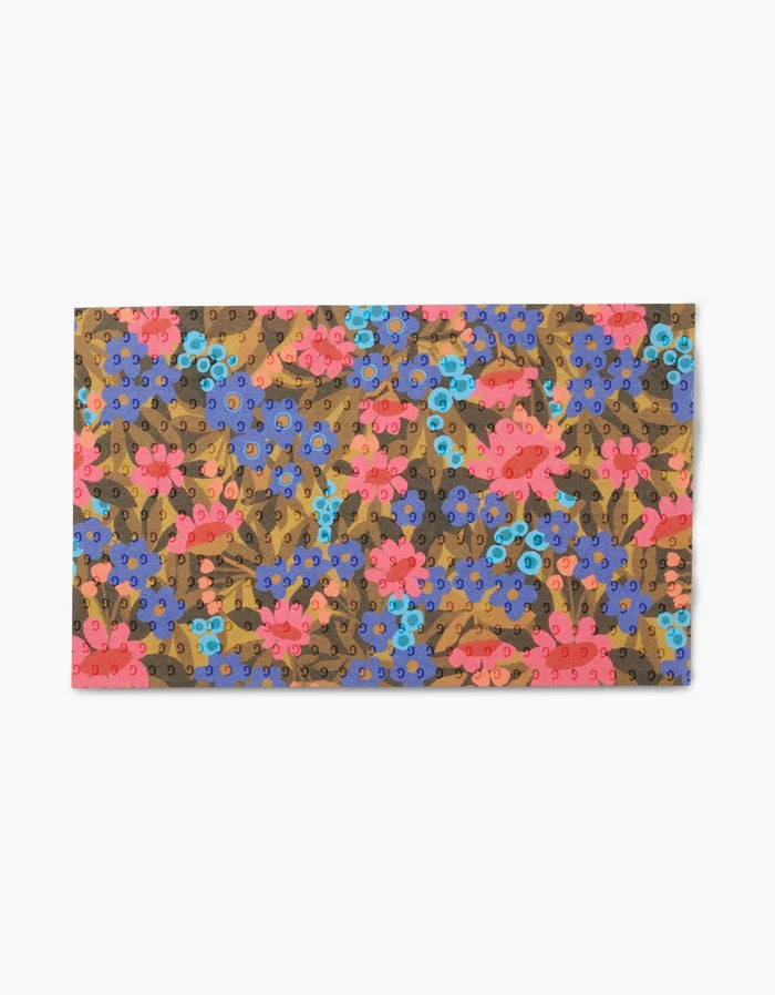 The Retro Garden mat by Lisa Nelson features a vibrant floral design with blue, pink, and purple flowers and green leaves on a brown background, made from recycled materials for an eco-friendly touch. Not Paper Towels.