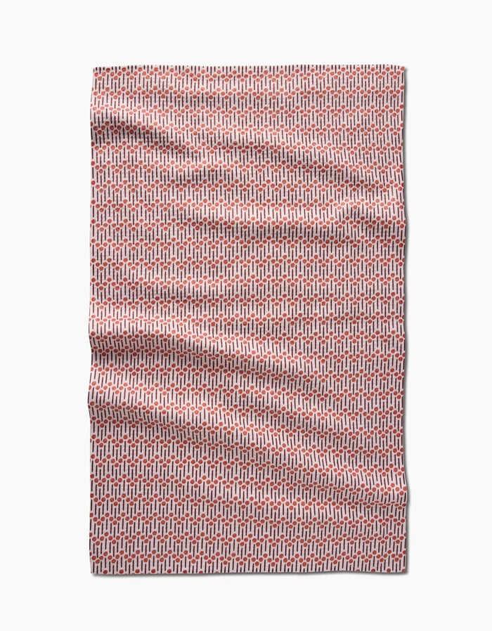 The Retro Geo tea towel by Teri the Butter features a red and white geometric pattern of small interlocking shapes. Made from recycled materials, its shown laid flat with light wrinkles on a plain white background.