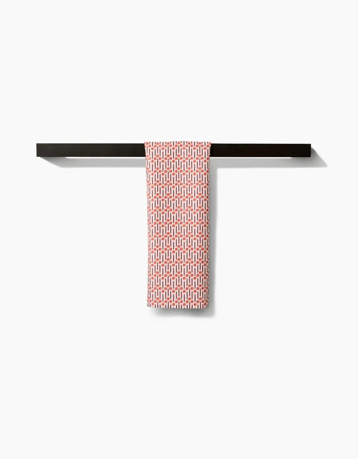 The Retro Geo Bar Towel by Teri the Butter, featuring a red and white pattern and made from recycled materials, hangs neatly over a sleek black towel bar against a plain white background.