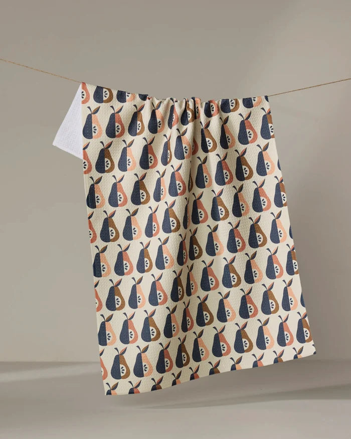 The Megan Kampa "Retro Pears" kitchen tea towel, made from recycled materials, features a navy blue, beige, and muted orange abstract pear pattern. It hangs from a string against a light background.