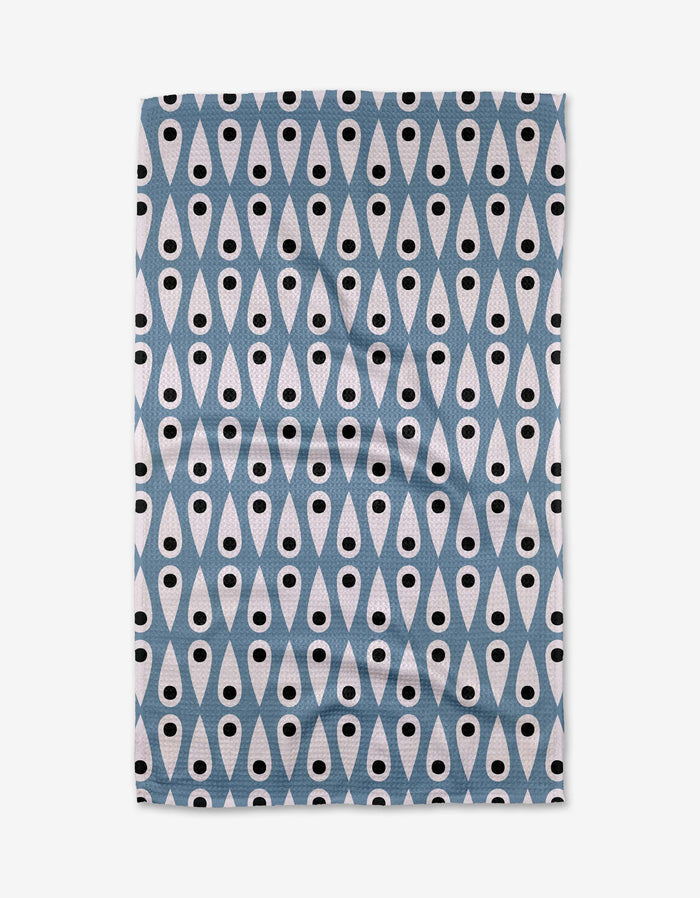The Anette Heiberg Retro Rain tea towel displays a repeating geometric pattern of blue diamonds and white teardrops with black dots, arranged in vertical rows on a white background.