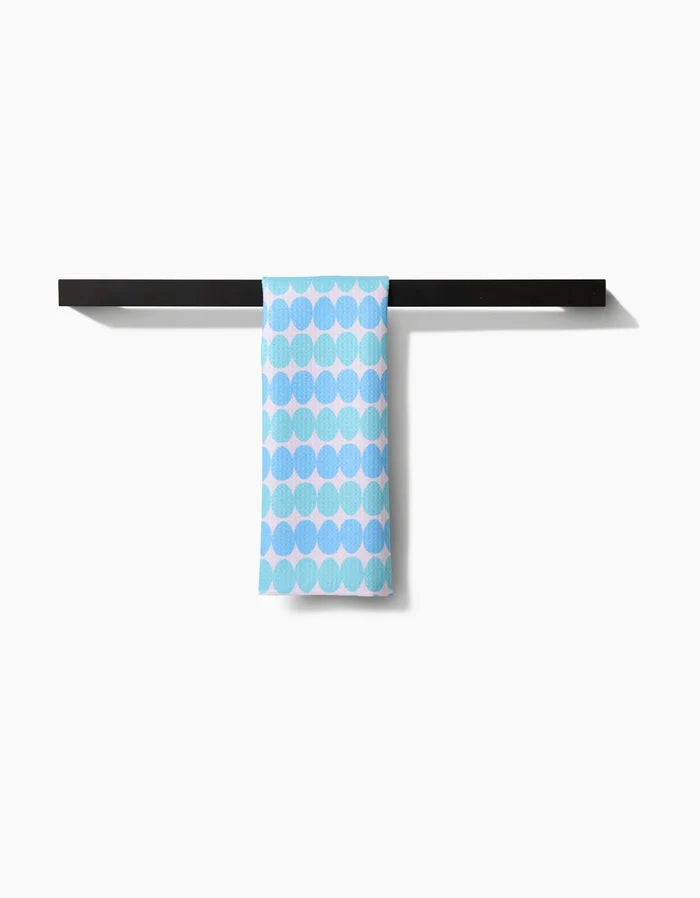 The Kayla Ann Robins Egg Bar Towel, featuring light blue dots on soft Geoweave fabric, hangs over a sleek black towel bar against a white background. It offers superior absorbency and quick drying.