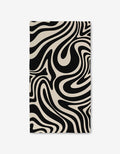 The GEOMETRY Rolling Retro Luxe Bath Towel showcases Geoweave technology and a bold black-and-white wavy zebra-stripe pattern, giving it a dynamic, modern look.