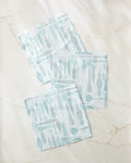Three Romy Wares blue and white super-absorbent dishtowels by Amy MacCready, featuring various utensil patterns, are arranged with slight overlap on a light marble-like surface.