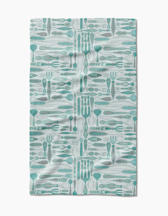 The Romy kitchen towel by Amy MacCready features a teal and gray utensil pattern on white Geoweave fabric. Ultra-absorbent, eco-friendly, and stylish, it boasts a slightly wrinkled finish for added charm.