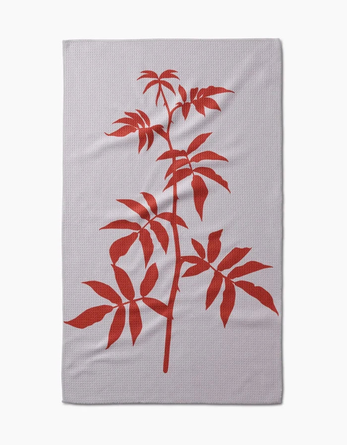 The Rose tea towel by PrintedPlant is a light grey rectangular Geoweave fabric towel, featuring a large bold red illustration of a leafy plant branch diagonally across the surface.