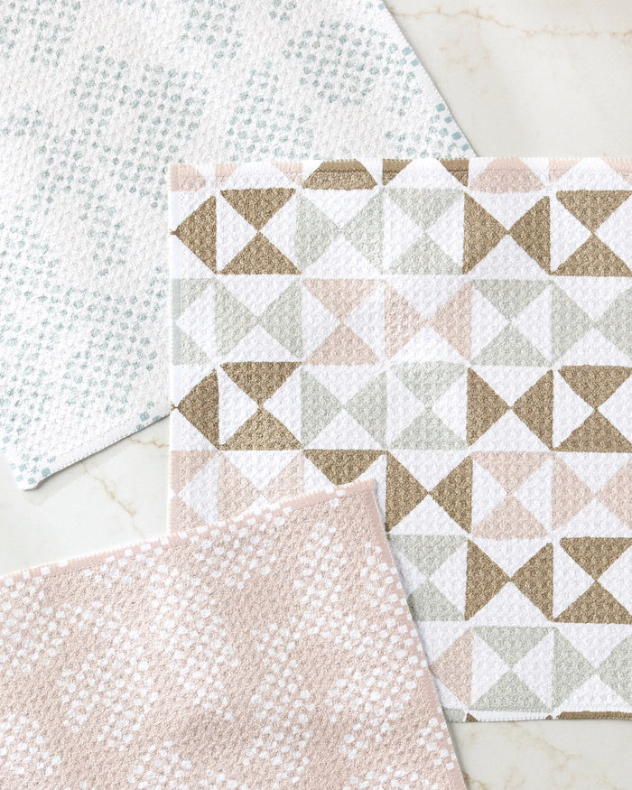 Studio Jeannot’s Rubix Pixie mats, made from recycled materials, are displayed on a light surface. One features geometric pastel triangles, while the other two showcase soft dot patterns in light blue and pink.