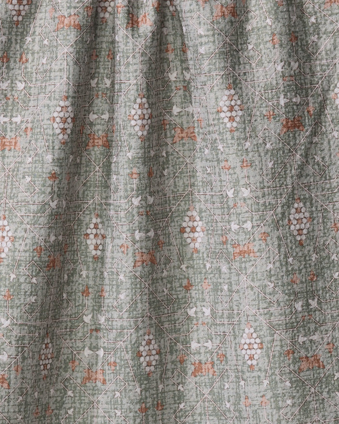 A close-up of the Rulon Sage fabric by Becki Owens reveals intricate geometric and floral patterns in muted green, white, and rust, creating a timeless aesthetic with its textured, slightly gathered design.