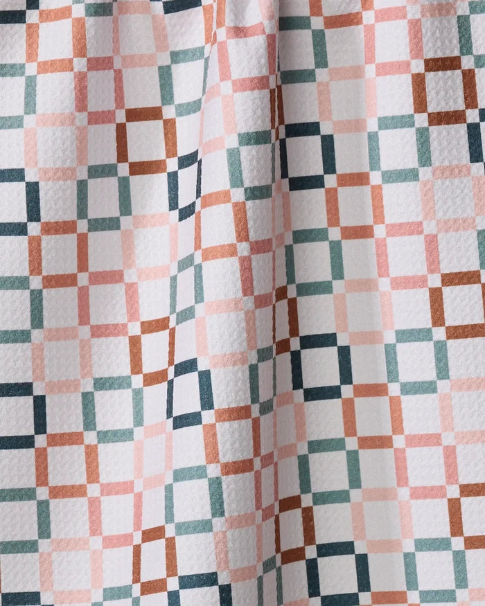 A close-up of the Russet Crossroads recycled kitchen towel by Charlie Rowan Designs, showing a plaid pattern in pastel pink, green, brown, and navy blue on white with a textured surface and a central fold.
