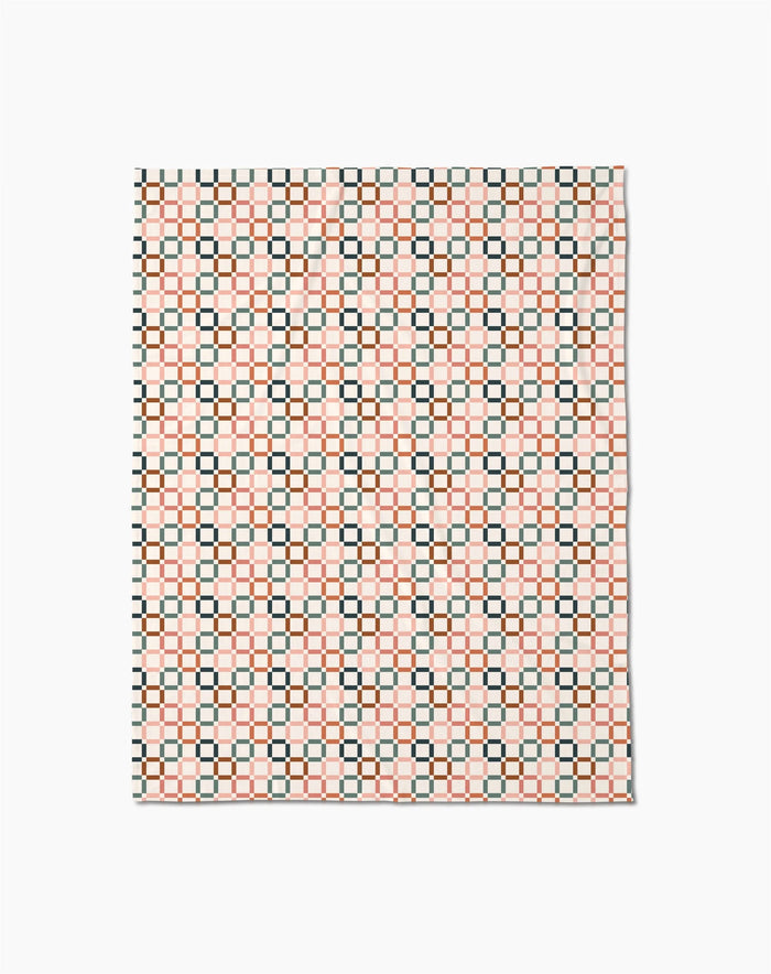 The Russet Crossroads Butter Blanket by Charlie Rowan Designs features a geometric grid of black, red, and cream squares on white, crafted from recycled materials for an eco-friendly touch.
