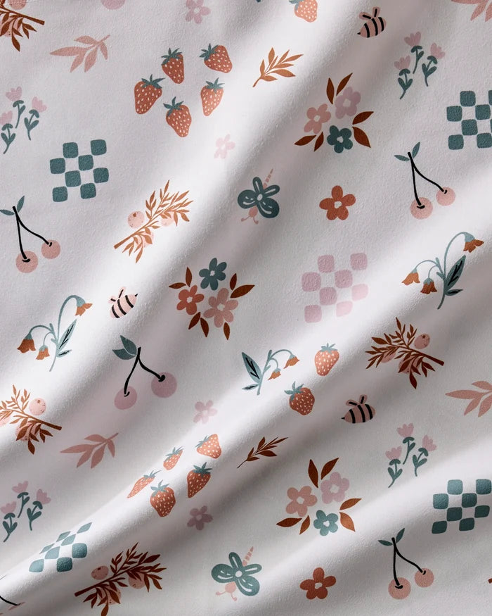 Russet Meadow by Charlie Rowan Designs features white fabric with strawberries, cherries, bees, flowers, butterflies, and geometric shapes in soft pinks, browns, teals, and oranges—ideal for charming reusable or dinner napkin sets.