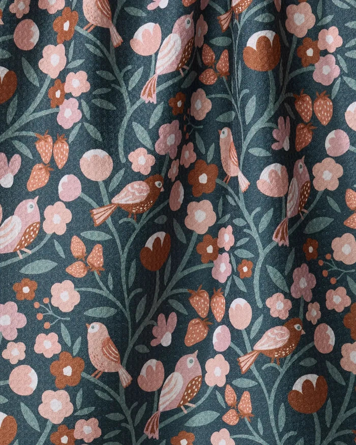 Russet Park Lane by Charlie Rowan Designs features pink, peach, and rust birds, flowers, and leaves on dark green. Made from quick-drying recycled materials, the fabric is slightly gathered for soft folds and shadows.