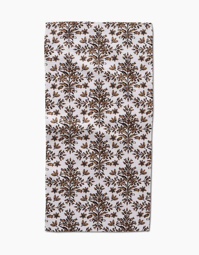 The Rustic Lacy Tile Natural by Hufton Studio is a rectangular white recycled kitchen towel with a repeating brown and gold botanical pattern of symmetrical tree motifs arranged in rows.