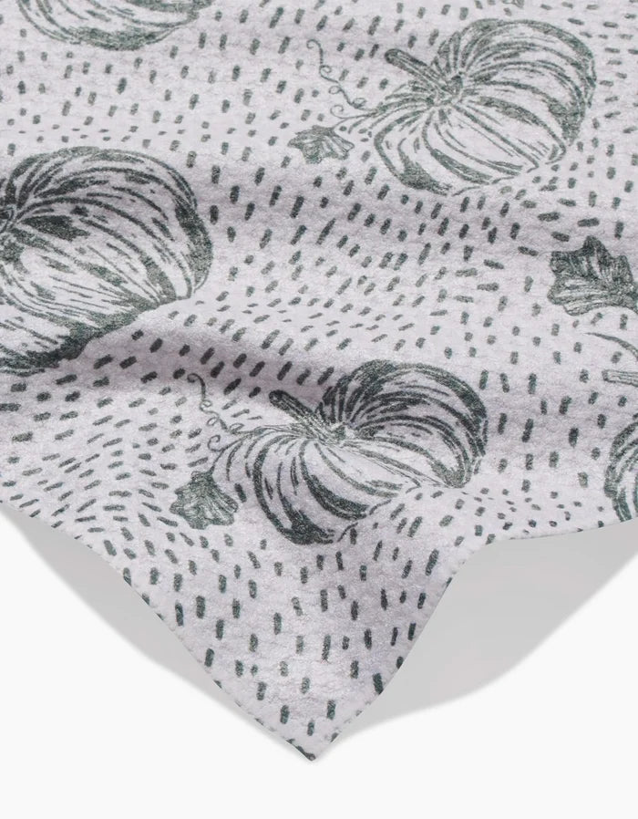 A light gray Sage Pumpkin Field bar towel by Charlie Rowan Designs features a black pumpkin and dotted line pattern. The fabric is slightly wrinkled, with the edge visible in the lower corner.