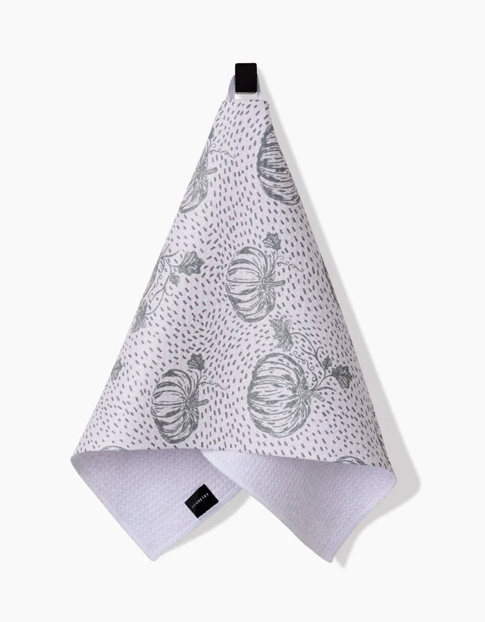 The Sage Pumpkin Field Bar Towel by Charlie Rowan Designs, crafted from Geoweave fabric, features gray pumpkin illustrations and dotted patterns. It hangs from a black loop against a white background.