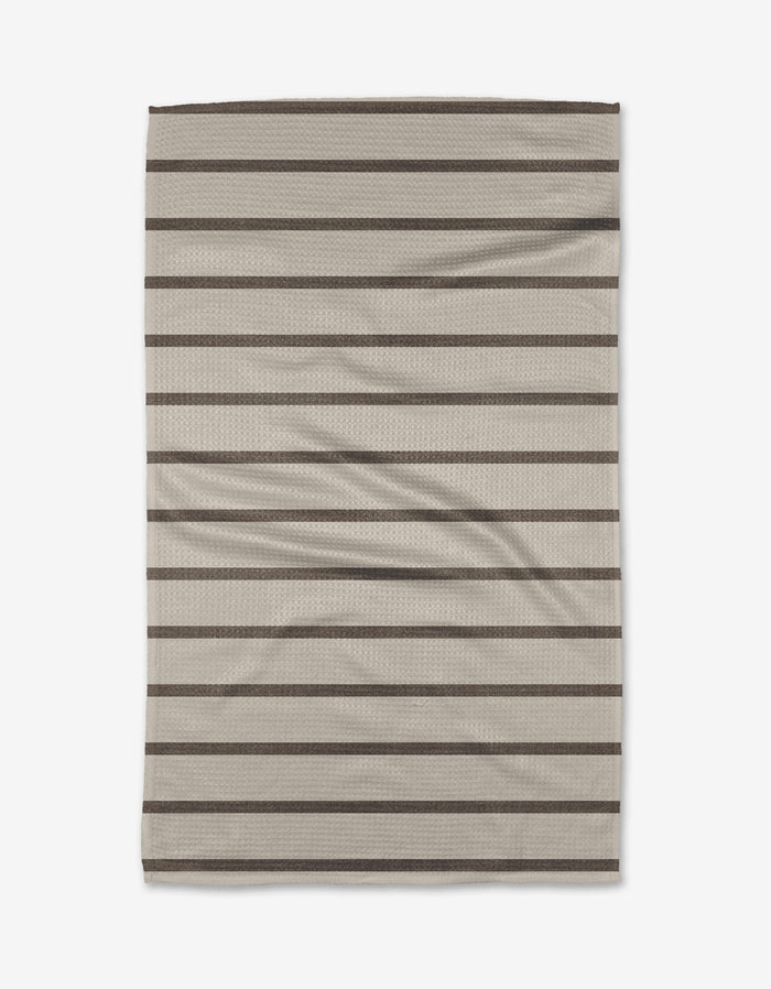The Salt Air Stripe dish towel by Jenny Keller features a beige rectangular design with horizontal dark brown stripes. Soft and slightly wrinkled, it’s perfect for everyday kitchen use.