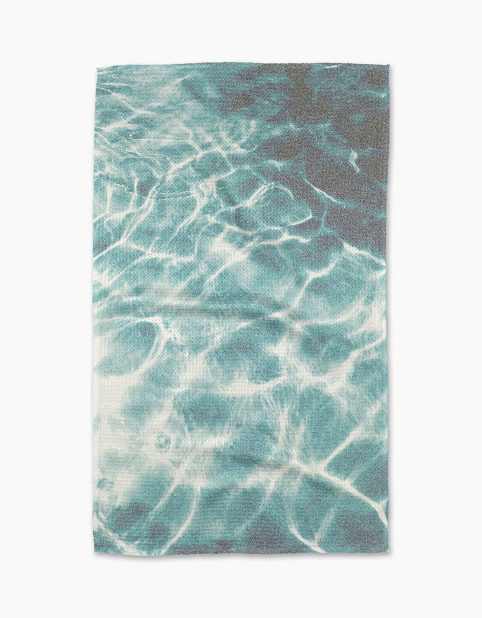 The Geometry Saltwater Glow Tea Towel features a print of sunlight on clear blue water, evoking a swimming pool, and is made from absorbent Geoweave fabric.