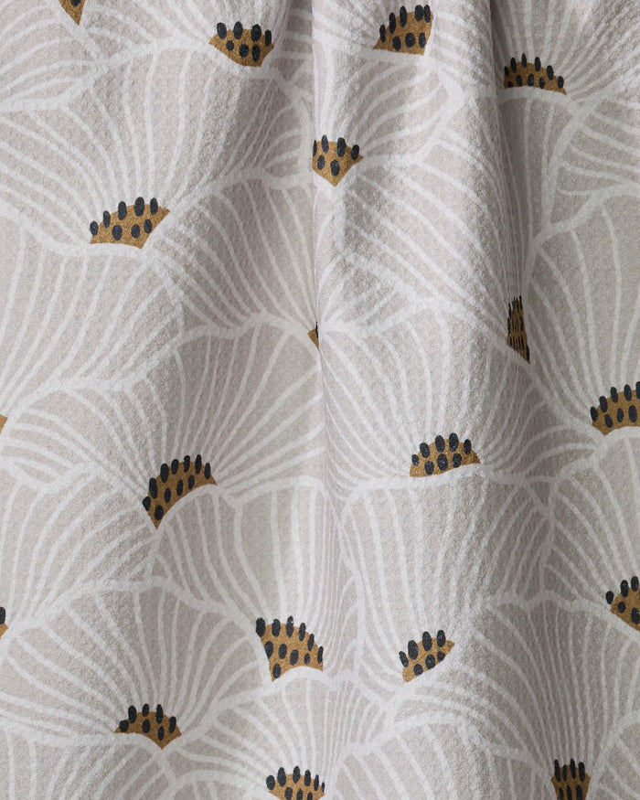 A close-up of the Amy MacCready San Diego tea towel, shown on a white background with large abstract white flowers outlined in light grey and detailed with black and gold dots at the center.