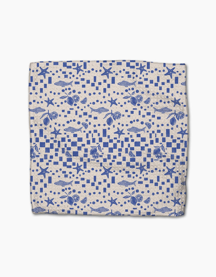 The Santorini Tile dishcloth by Geometry features a blue nautical seashell and starfish pattern with geometric shapes on white, crafted from durable Geoweave fabric for superior cleaning.
