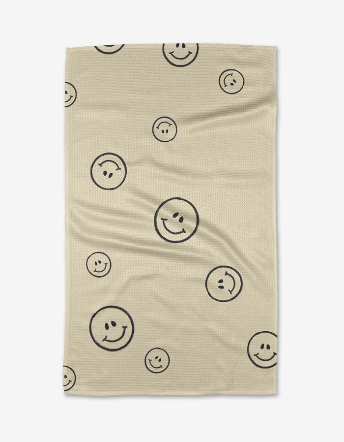 The Say Cheese blanket by Kelsi Fullmer is beige, made from recycled materials, and decorated with black outlined smiley faces in various sizes scattered across the surface.