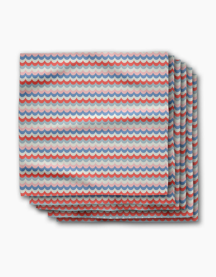 Four folded Scallop Stripes dinner napkins by Geometry, made from recycled Geosuede fabric with a blue, red, and white wave pattern. Stacked slightly offset on a white background—eco-friendly and stylish for any table.