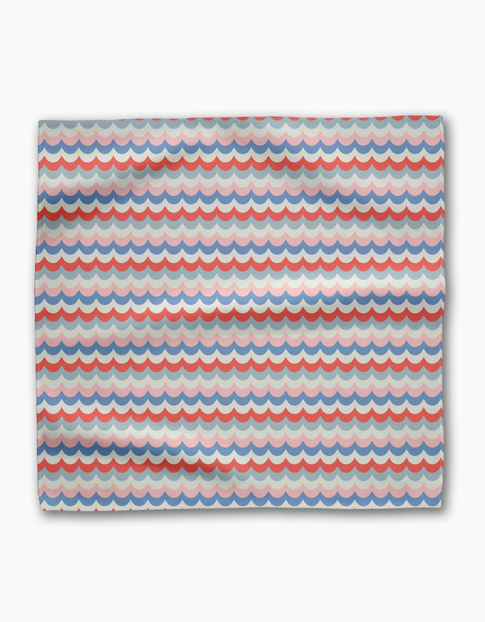 The Geometry Scallop Stripes dinner napkin is made from recycled Geosuede fabric with a red, blue, and gray scallop wave pattern on white, featuring horizontal rows of semi-circular shapes.