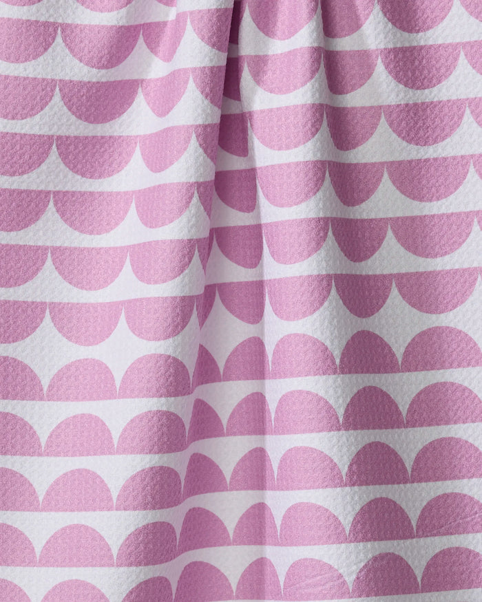 Close-up of The Buy Guide’s Scallops - Pink eco-friendly dish towel, featuring a reusable design with soft folds and a repeating pattern of pink semi-circles in horizontal rows on white.