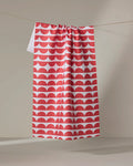 The Buy Guide’s Scallops - Red tea towel, ultra-absorbent and featuring a red and white scallop pattern, hangs from a clothesline against a neutral background.