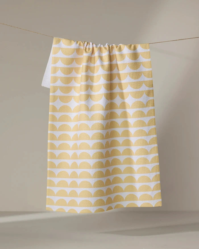 The Buy Guide's Scallops - Yellow tea towel features a yellow and white semicircle pattern and hangs on a string against a neutral backdrop.