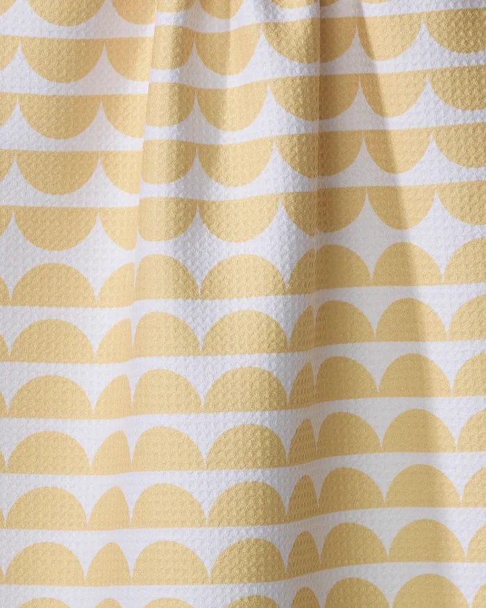 A close-up of The Buy Guide’s Scallops - Yellow tea towel shows its white, textured surface with a repeating pattern of yellow semi-circles and lines in a geometric, scalloped design.