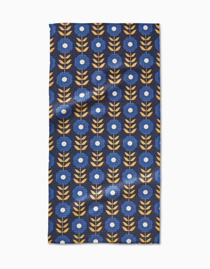 The Scandi Floral Bar Towel by Megan Kampa features a modern, evenly spaced geometric pattern of yellow stems and blue flowers on dark blue Geoweave fabric, blending eco-friendly design with Scandinavian style.