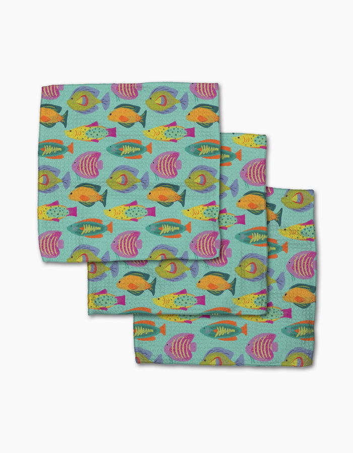 The Geometry Schooling set includes three cloth napkins featuring a colorful fish pattern on light teal, made from post-consumer recycled materials—an eco-friendly and cheerful addition to your table.