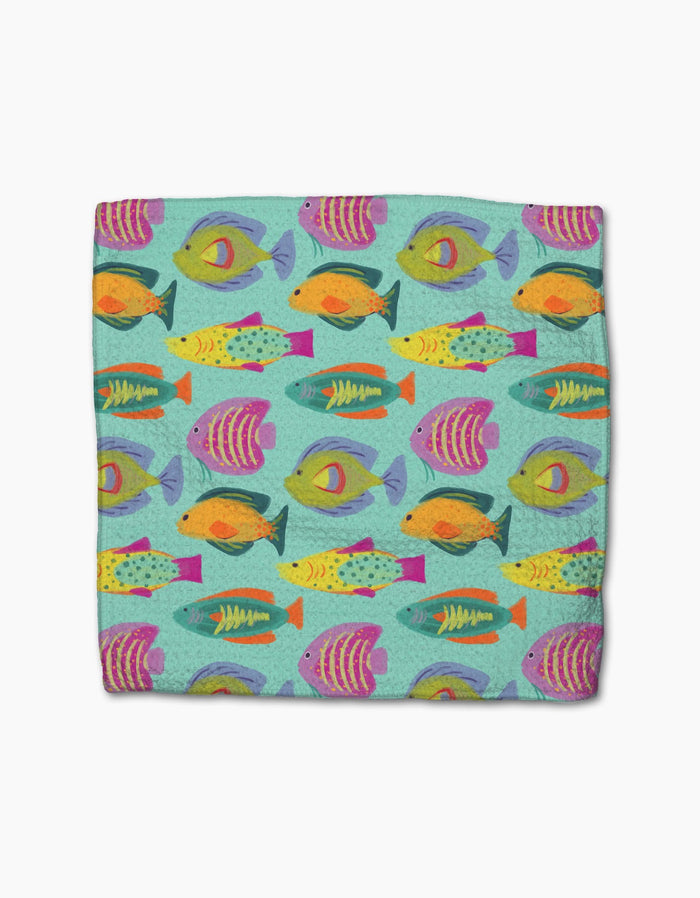 The Geometry Schooling blanket is super-absorbent and features a vibrant design of colorful fish in orange, yellow, purple, pink, and green swimming on a light teal background.