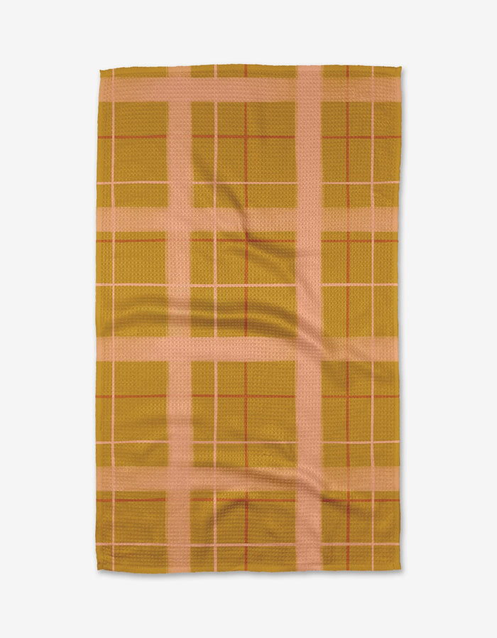 The Elisabeth Wing Scotland Yard tea towel features a mustard yellow and light pink plaid with wide and narrow intersecting lines. Made from soft Geoweave fabric for enhanced absorbency, its shown laid flat on a white background.