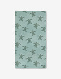 The Katie OShea Sea Turtles Luxe Bath Towel showcases sea turtles among white coral on a light teal background, made with Geoweave technology for an ultra-absorbent, premium feel.