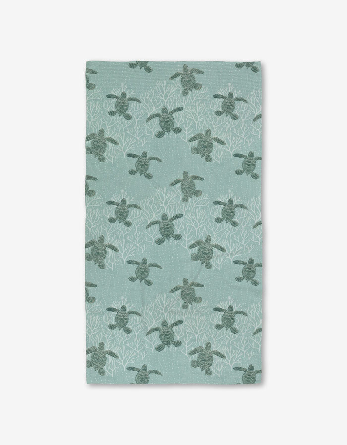 The Katie OShea Sea Turtles Luxe Bath Towel showcases sea turtles among white coral on a light teal background, made with Geoweave technology for an ultra-absorbent, premium feel.